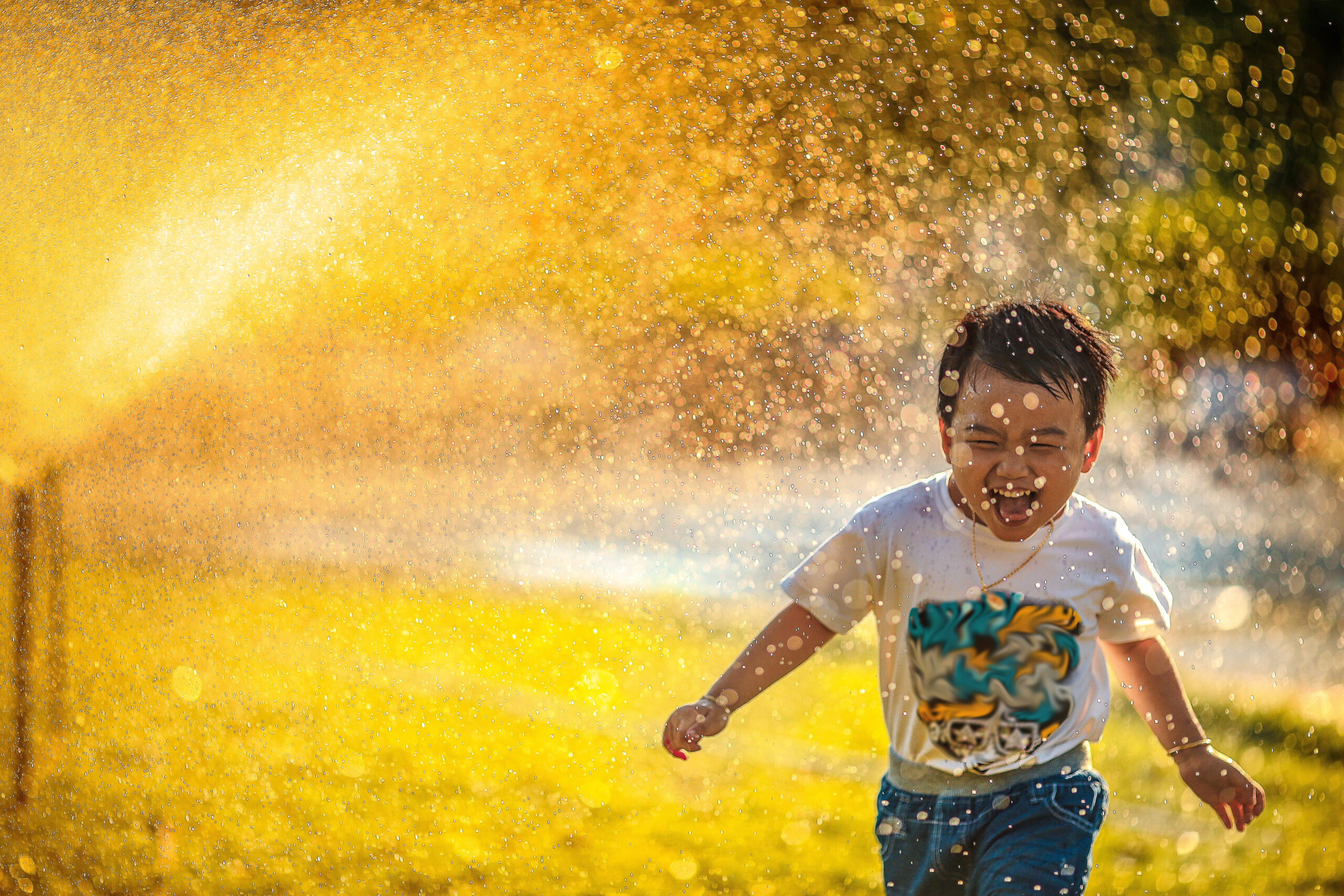 Background photo of a child running through a sprinkler